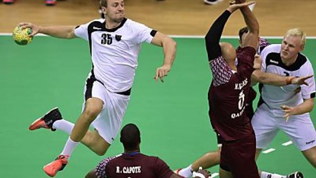 Ein Handballspieler springt, um den Ball zu werfen, während andere Spieler zusehen.