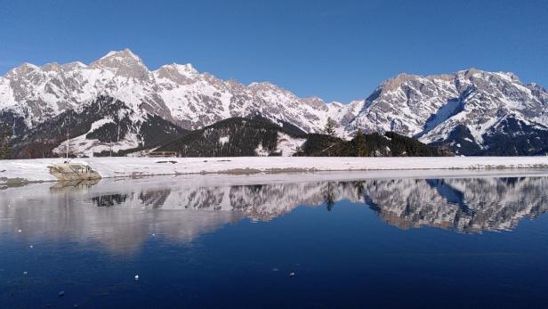 Schneebedeckte Berge spiegeln sich in einem ruhigen See.