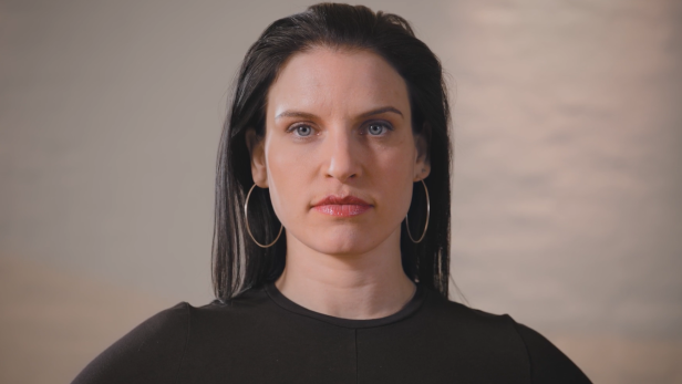 Eine Frau mit dunklen Haaren und Ohrringen blickt in die Kamera.