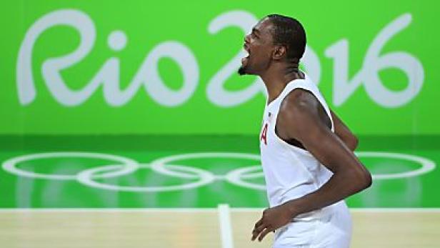 Ein Basketballspieler jubelt vor dem Hintergrund des Logos der Olympischen Spiele 2016 in Rio.