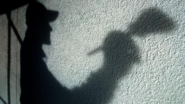 Der Schatten einer Person mit Kappe an einer Wand.