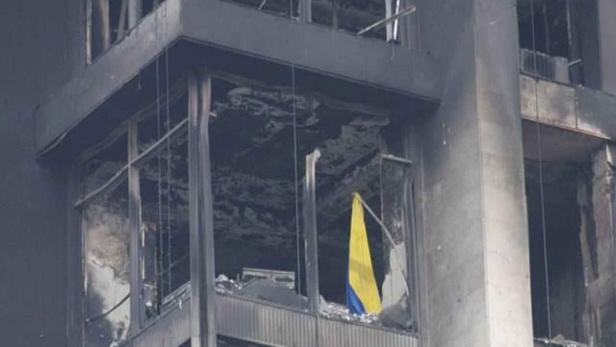 Ein beschädigtes Gebäude mit einer blau-gelben Flagge in einem Fenster.