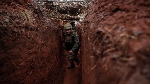 Ukrainian service member walks along a trench at a position on the front line near the city of Novoluhanske