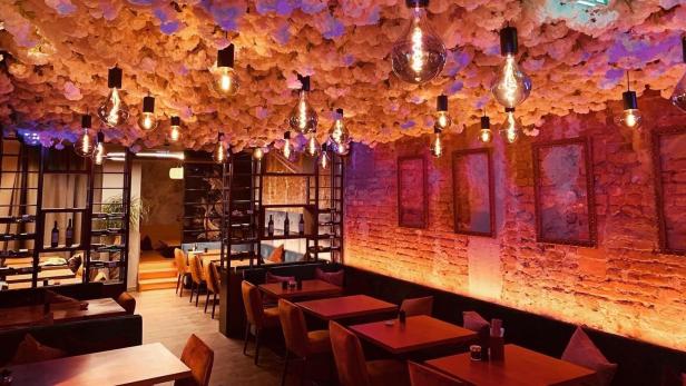 Ein Restaurant mit Blumendecke und Edison-Glühbirnen in warmem Licht.