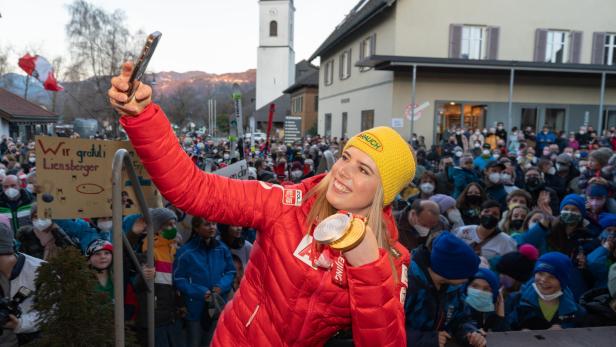 Katharina Liensberger macht ein Selfie mit ihren Medaillen vor einer jubelnden Menschenmenge.