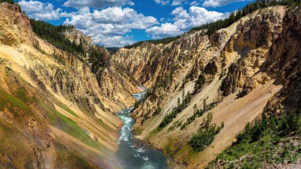 Ein Regenbogen überspannt den tosenden Wasserfall in einer tiefen Schlucht.