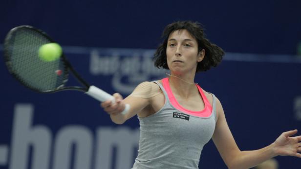 Eine Tennisspielerin schlägt einen Ball mit ihrem Schläger.