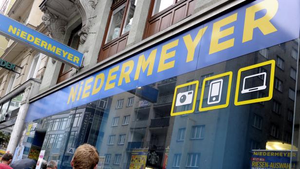 Das Geschäft „Niedermeyer“ mit gelber Schrift auf blauem Grund bietet Kameras, Smartphones und Laptops an.