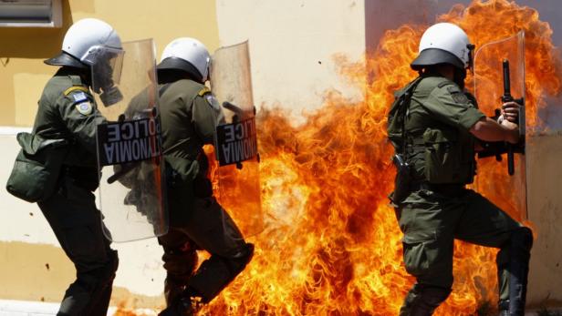 Policemen try to escape a fire from a petrol bomb during riots at a May Day rally in Athens May 1, 2010. REUTERS/John Kolesidis (GREECE - Tags: POLITICS BUSINESS EMPLOYMENT CIVIL UNREST)