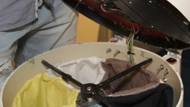 Ein Mann befüllt eine Art Wäschetrockner mit Kleidung.