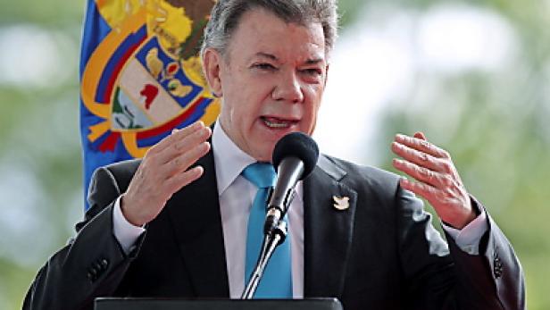 Juan Manuel Santos hält eine Rede vor der kolumbianischen Flagge.
