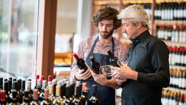 Zwei Männer betrachten Weinflaschen in einem Weinladen.