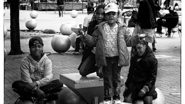 Eine Gruppe Kinder posiert auf einer städtischen Skulptur in Schwarzweiß.