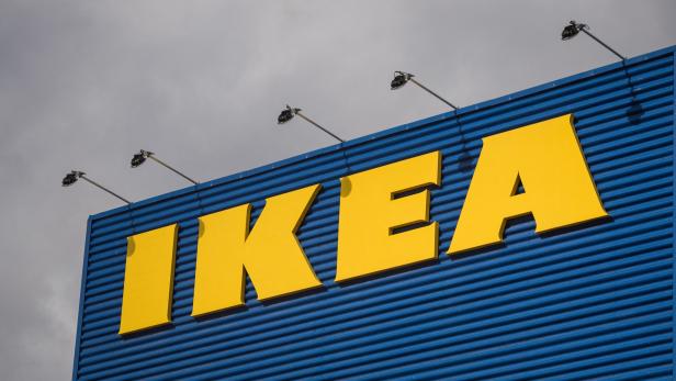 Das gelbe IKEA-Logo an einer blauen Fassade unter einem bewölkten Himmel.