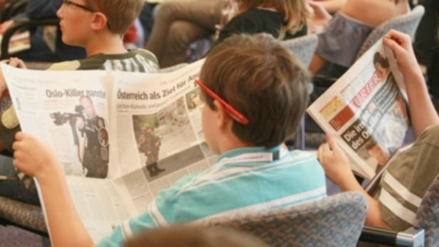 Mehrere Kinder lesen Zeitungen, darunter den „Kurier“, mit Artikeln über den Oslo-Killer.