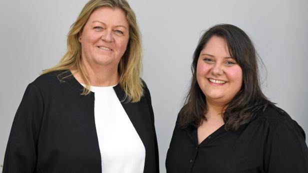 Zwei Frauen lächeln in die Kamera.