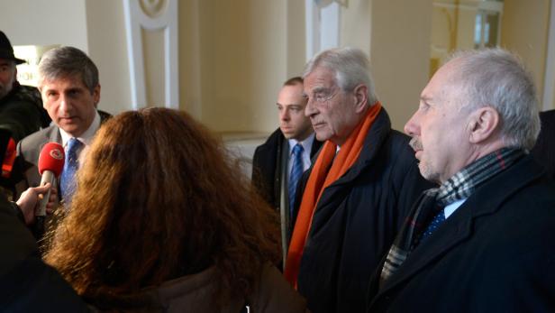 Mehrere Personen, darunter ältere Männer, werden von Reportern interviewt.