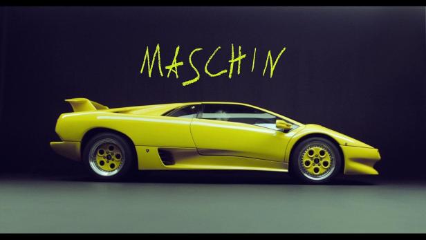 Ein gelber Lamborghini Diablo vor einem dunklen Hintergrund mit dem Wort „Maschin“ darüber.