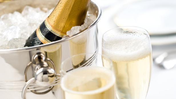 Eine Flasche Champagner in einem Eiskübel neben zwei gefüllten Gläsern.