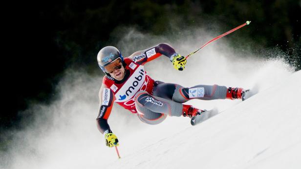 Ein Skirennfahrer rast mit hoher Geschwindigkeit eine schneebedeckte Piste hinunter.