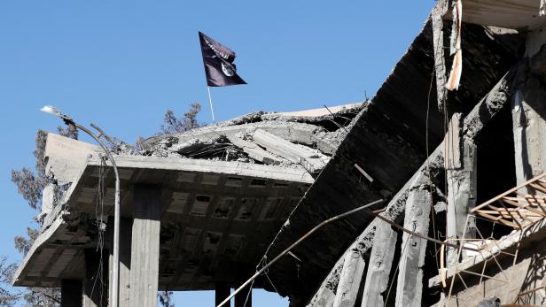 FILE PHOTO: A flag of Islamic State militants is pictured above a destroyed house near the Clock Square in Raqqa