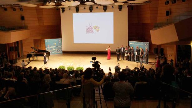 Eine Preisverleihung findet in einem Konzertsaal vor Publikum statt.