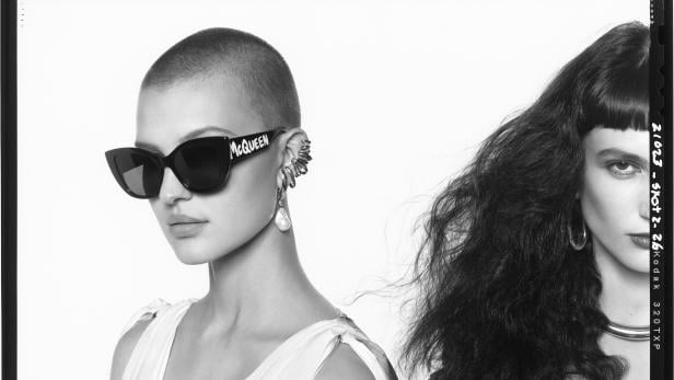 Schwarz-Weiß-Foto zweier Frauen, eine mit „McQueen“-Sonnenbrille und Ohrschmuck.