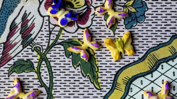 Gelbe Schmetterlingskekse liegen auf einem gemusterten Hintergrund.