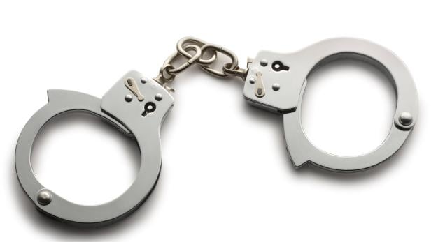 Eine silberne Handschelle liegt auf einem weißen Hintergrund.