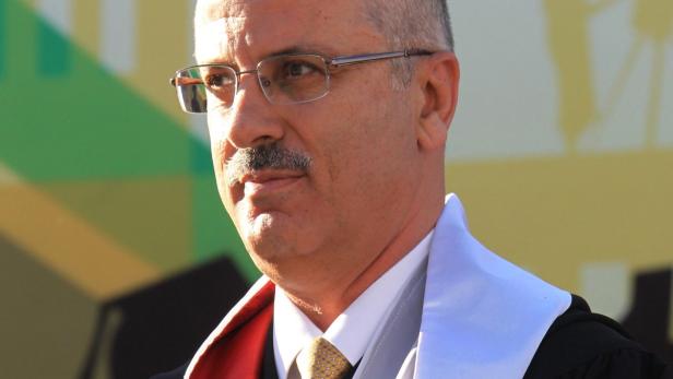 Ein Mann mit Brille und Schnurrbart trägt eine akademische Robe.