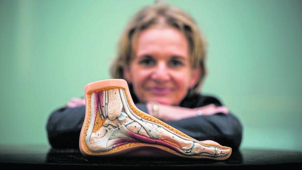 Eine Frau präsentiert ein anatomisches Modell eines menschlichen Fußes.
