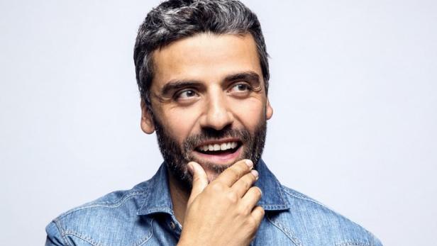 Oscar Isaac lächelt und blickt nachdenklich zur Seite.