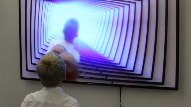 Eine Person betrachtet einen Fernseher mit einer Tunnel-artigen Grafik.
