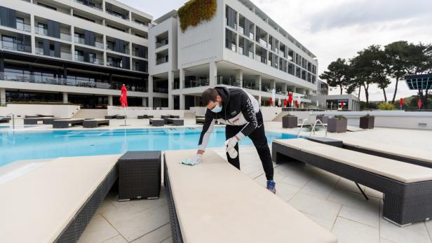 Worker disinfects deck chairs in Hotel Parentium Plava Laguna in Porec