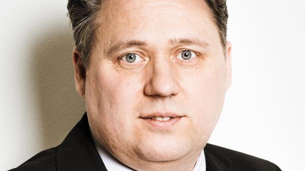 Ein Mann mit Anzug und Krawatte blickt in die Kamera.