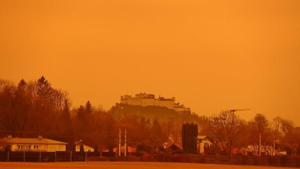 Die Festung Hohensalzburg überragt eine Landschaft in orangefarbenem Licht.