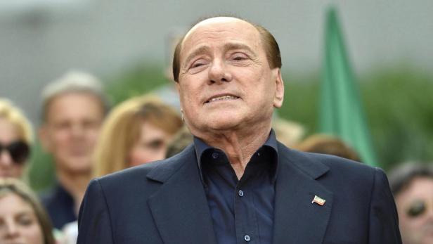 Silvio Berlusconi bei einer Veranstaltung mit einer italienischen Flagge am Revers.