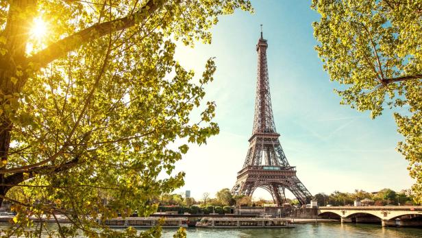 Der Eiffelturm in Paris, gesehen durch das Laub der Bäume.