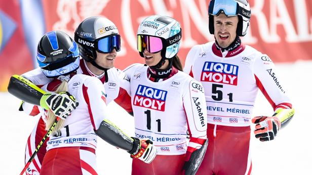 Vier Skirennläufer in Rennanzügen stehen zusammen im Schnee.