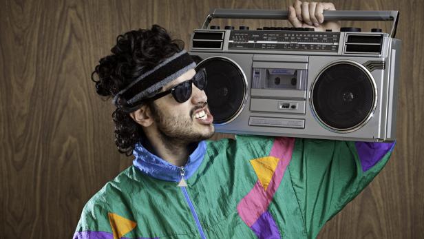 Ein Mann im 80er-Jahre-Stil trägt einen Ghettoblaster auf der Schulter.