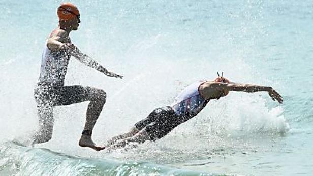 Zwei Triathleten steigen ins Wasser, um zu schwimmen.