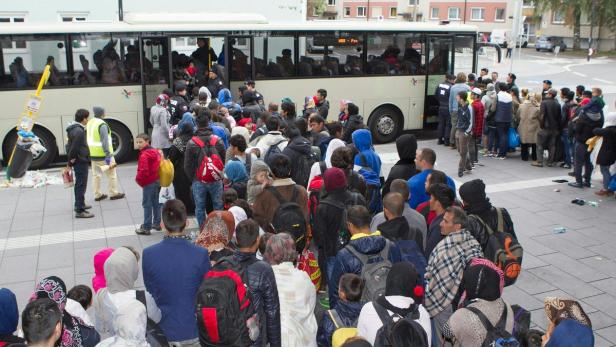 Eine große Menschenmenge steht vor einem Bus.