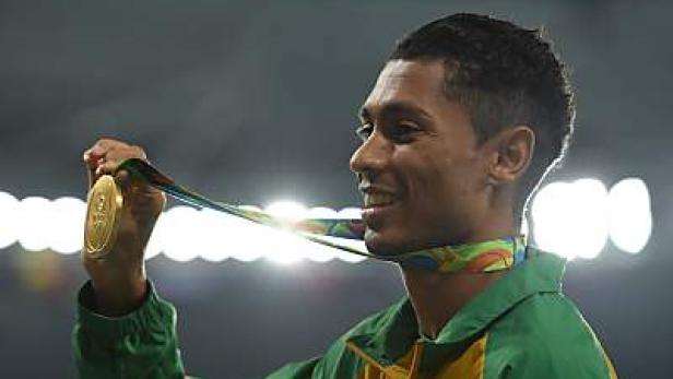 Ein lachender Athlet mit einer Goldmedaille um den Hals.