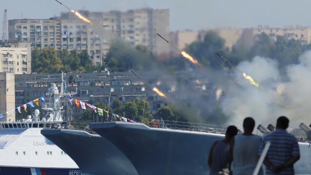 People watch a Russian warship firing missiles during a rehearsal for the Navy Day parade in Sevastopol