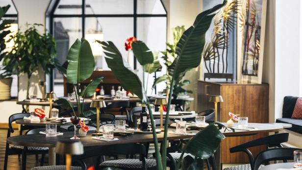 Ein elegant gedeckter Tisch in einem modernen Restaurant mit tropischen Pflanzen.