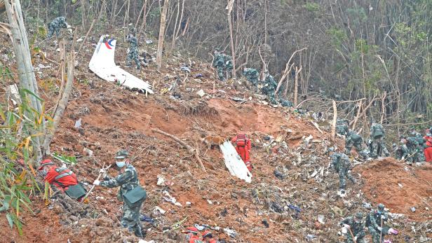 Rescuers search for the black boxes at a plane crash site in Tengxian county