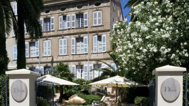 Das „La Galerie Dior“ in Grasse mit Tischen und Sonnenschirmen im Garten.