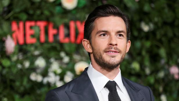 Jonathan Bailey vor einer Wand mit dem Netflix-Logo.