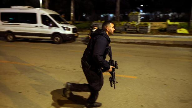 An Israeli security personnel runs at the scene of an attack in which people were killed by gunmen on a main street in Hadera, Israel