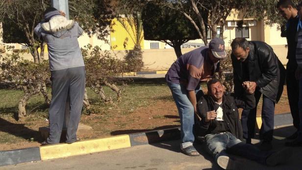 Eine Gruppe von Männern kümmert sich um einen Mann, der am Boden sitzt und Schmerzen zu haben scheint.